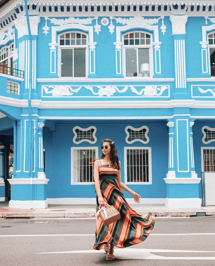 a woman walking across a street in front of a blue building