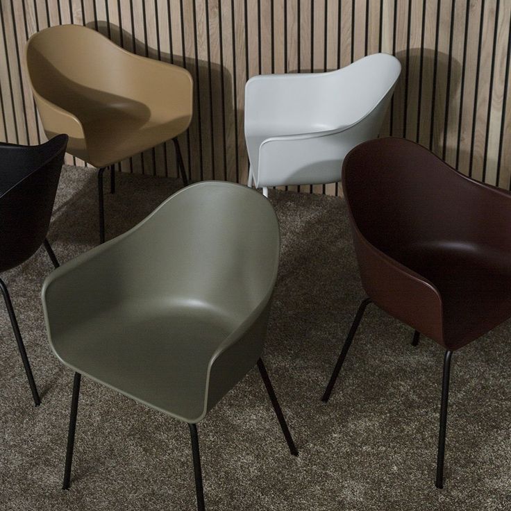 four different colored chairs sitting next to each other on top of a carpeted floor