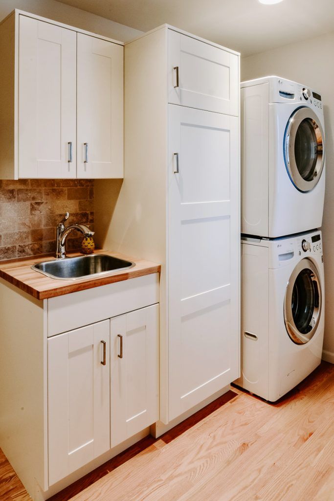 a washer and dryer sitting next to each other in a room with white cabinets