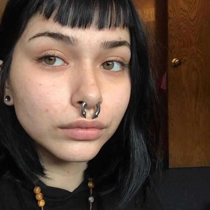 a young woman with piercings on her nose and nose ring is looking at the camera