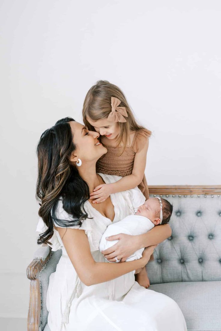 a woman holding a baby while sitting on top of a couch