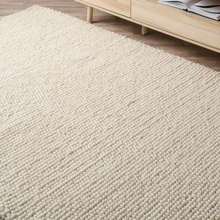 a large white rug on the floor next to a bed