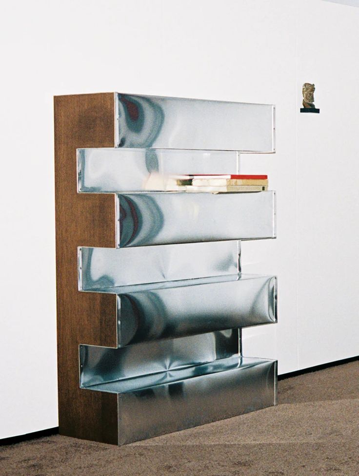 a tall metal shelf sitting on top of a wooden floor next to a white wall