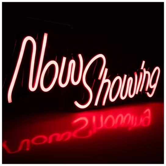 a neon sign that says now showing on it