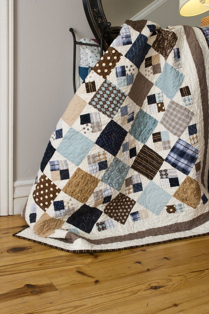 a quilted blanket sitting on top of a wooden floor next to a chair and mirror