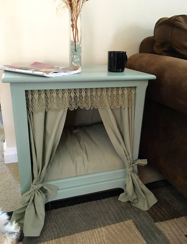 a small dog bed with curtains on the top and bottom, in front of a couch