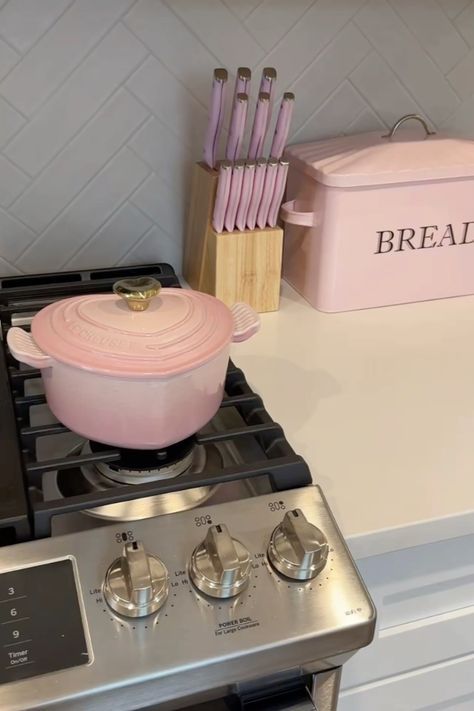 a stove top oven sitting inside of a kitchen next to a pink container with utensils on it