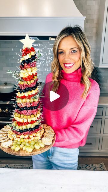 a woman holding a platter with food on it in the middle of a kitchen