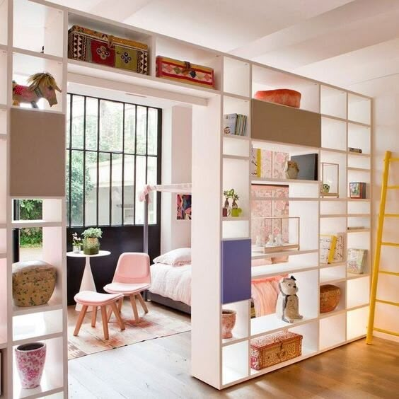 the interior of a room with white shelves and pink furniture