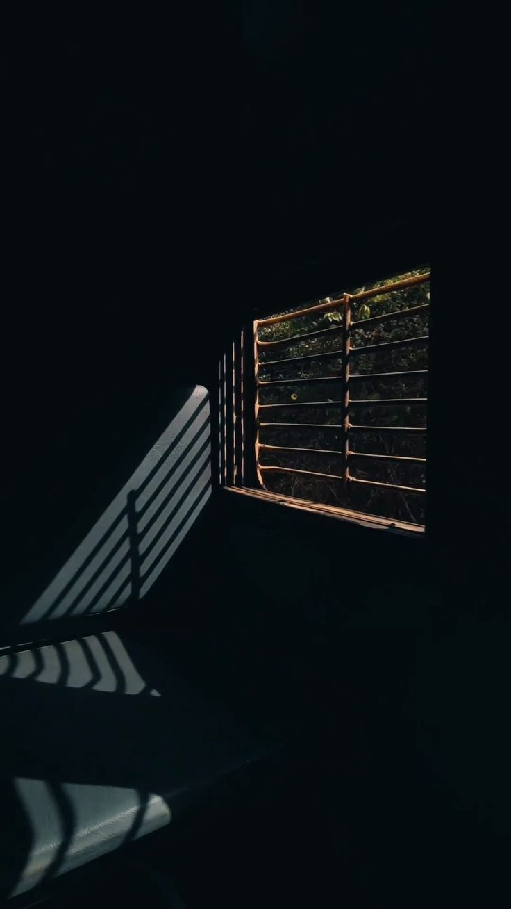 the shadow of a bench and window in a dark room