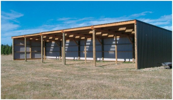 an empty building in the middle of a field with no grass on it and several open doors