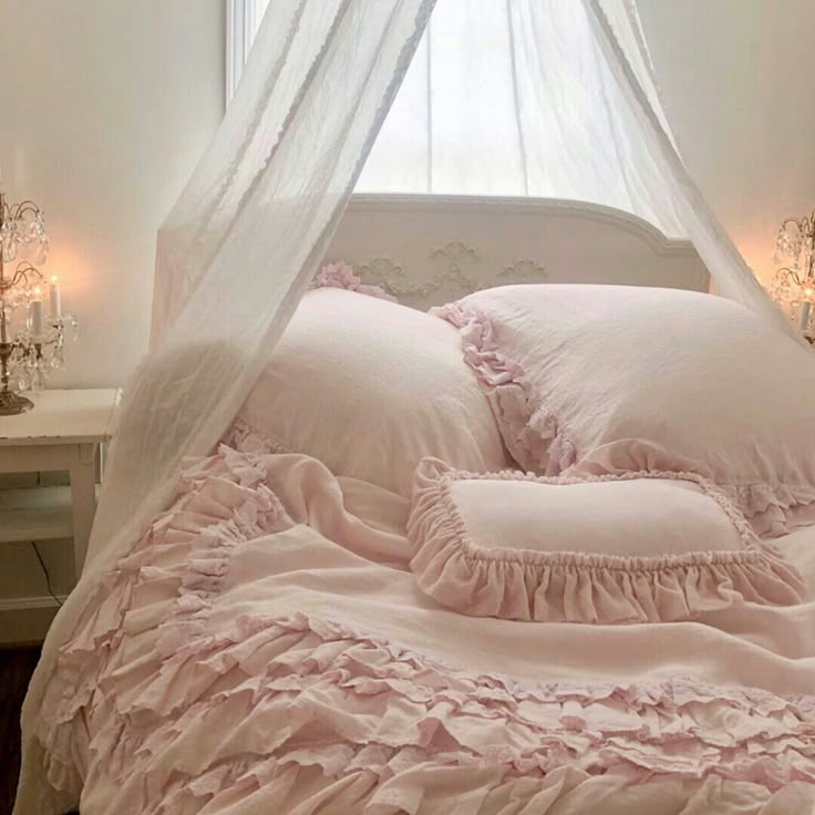 a white bed with pink ruffled sheets and pillows