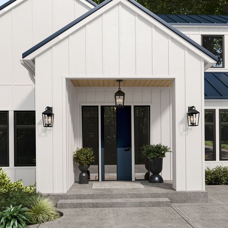 a white house with blue door and two planters