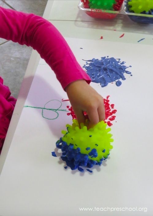 a child is playing with colored sprinkles on the paper and making an art project