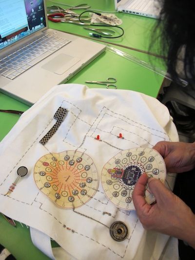 a person is working on an art project with scissors and buttons in front of a laptop