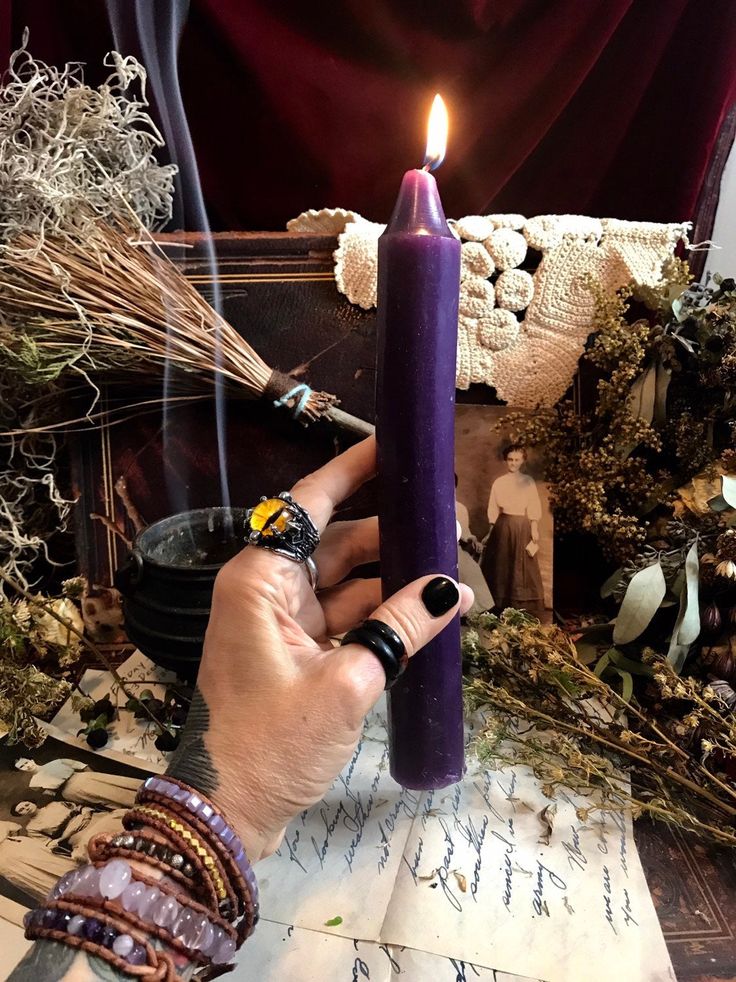 a person holding a purple candle in their hand