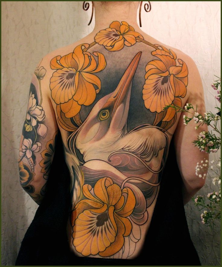 the back of a woman's tattoo with flowers and an unicorn on her shoulder