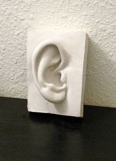 an ear sculpture sitting on top of a black table