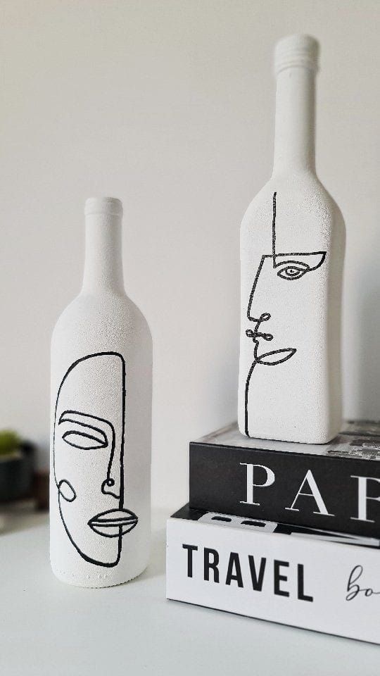 two bottles with faces painted on them sitting next to each other and books in front of them