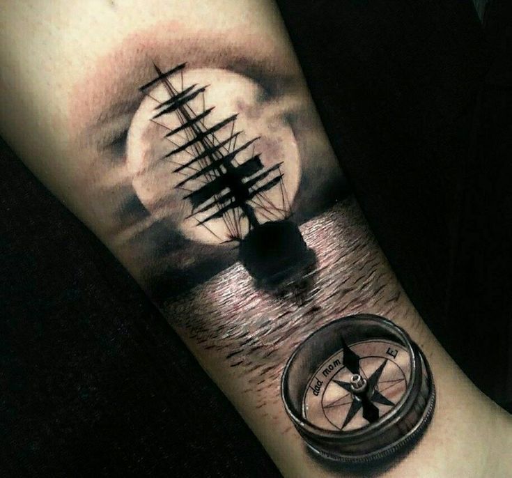 a man's arm with a ship and compass tattoo on it