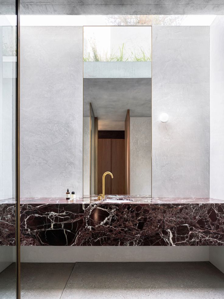 a bathroom with marble counter tops and gold faucet in the mirror above it