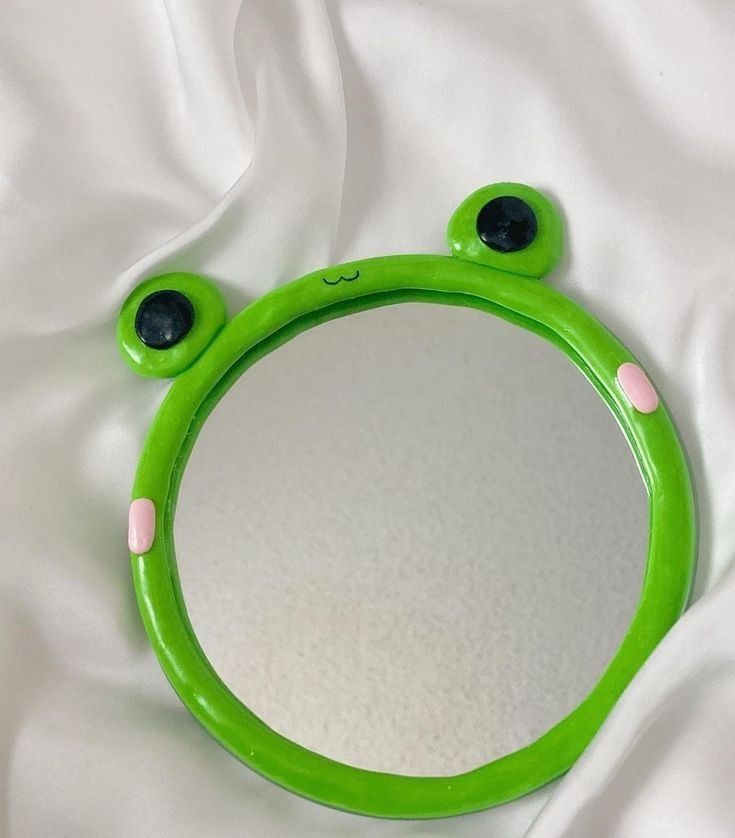 a green frog mirror sitting on top of a white sheet