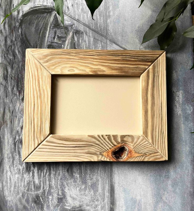 a wooden frame sitting on top of a table next to a potted green plant