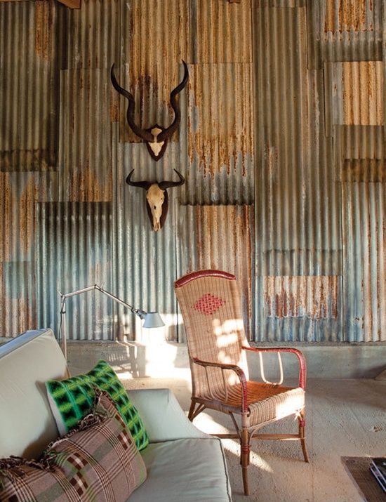 a living room filled with furniture and walls covered in rusted corrugated tin sheets,