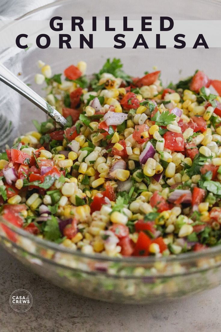 a glass bowl filled with corn salad on top of a table