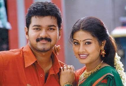 a man standing next to a woman in an orange shirt and green sari on the street