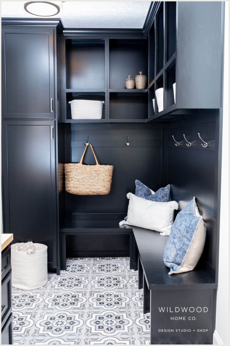 a mud room with black cabinets and white flooring