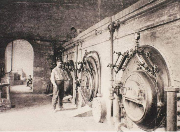 an old black and white photo of a man standing in front of a large machine