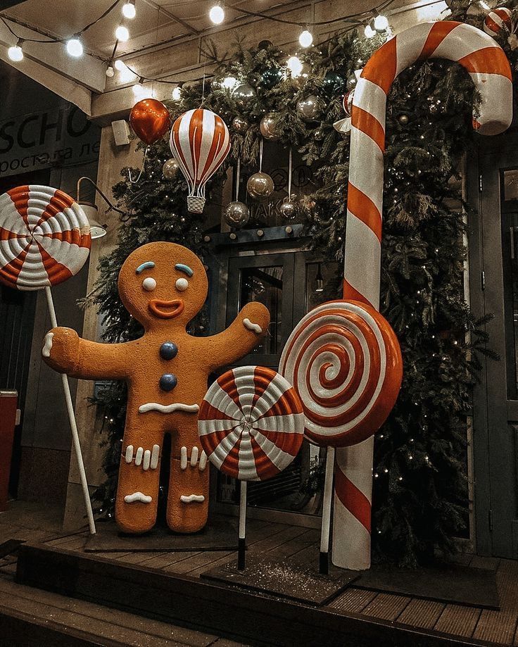 a gingerbread man and candy canes on display in front of a christmas tree