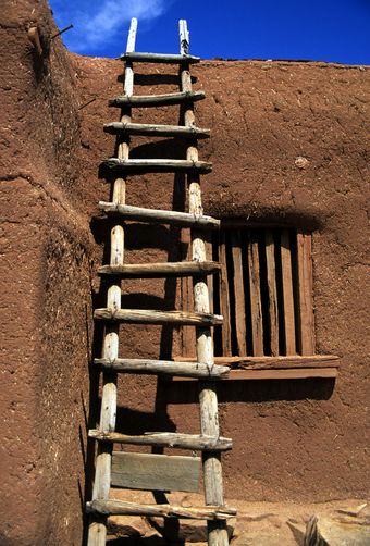 an old wooden ladder leaning against a adobe building