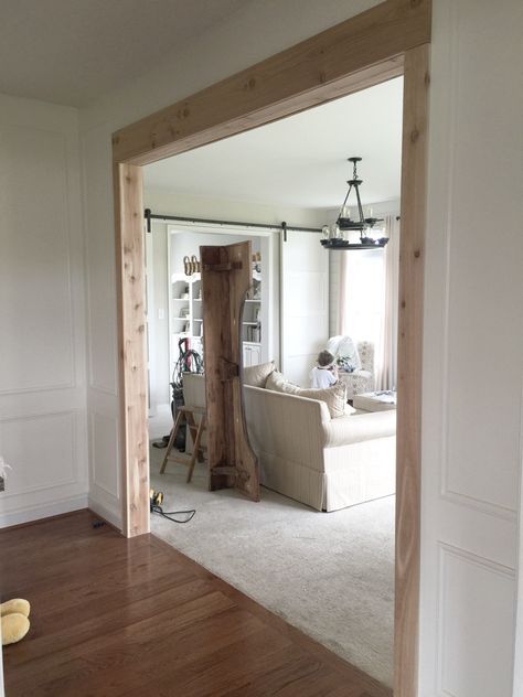 an open door leading to a living room with white walls and wood floors in it