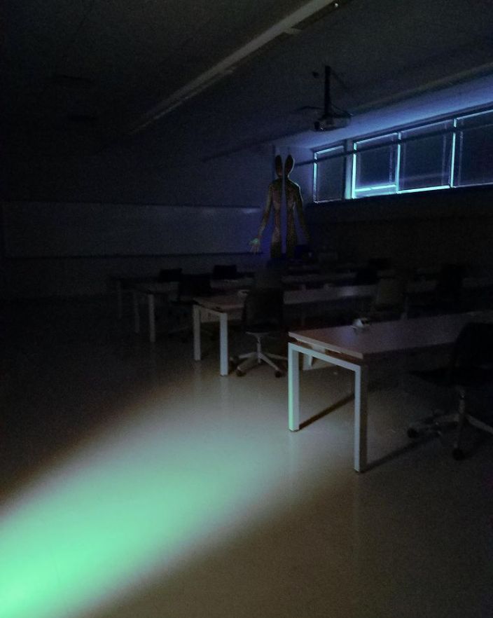 an empty room with tables and chairs lit up by green light coming from the ceiling