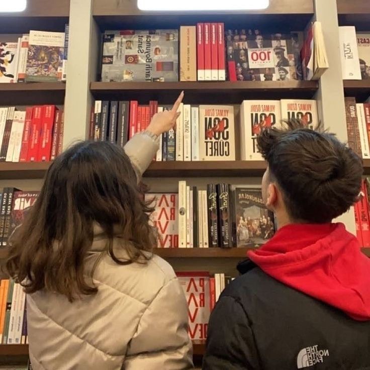 two people standing in front of a book shelf