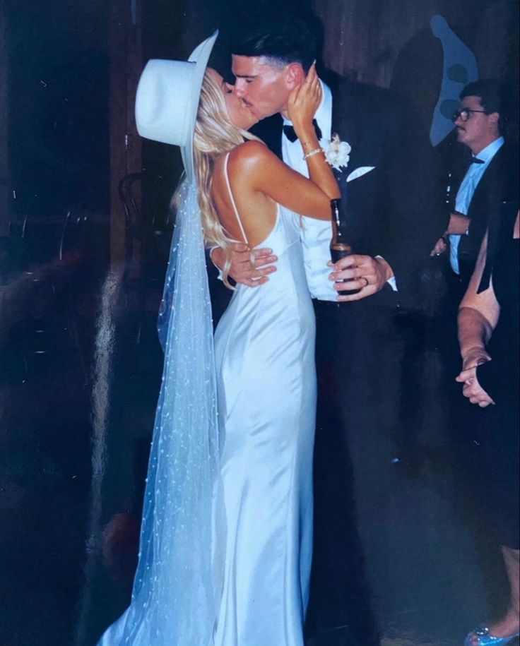 a man and woman in formal wear kissing each other on the dance floor at a wedding