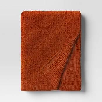 an orange blanket folded on top of a white wall