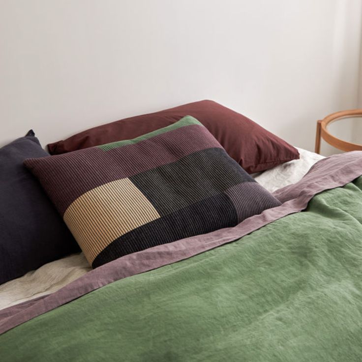 a bed topped with lots of pillows next to a window