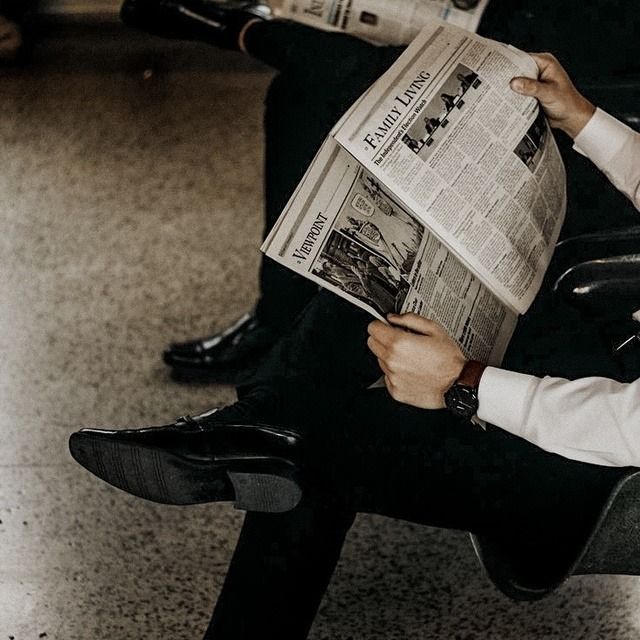 a man sitting in a chair reading a newspaper