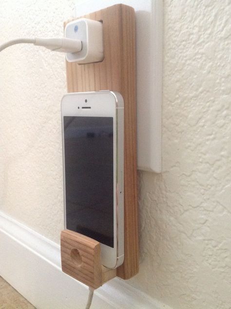 an iphone is plugged into a charger attached to a wall with a wooden holder