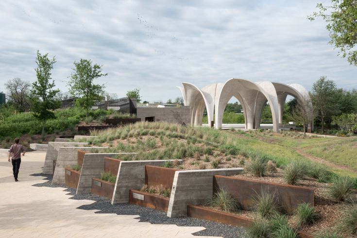 a person walking down a path next to an outdoor area with benches and plants on it