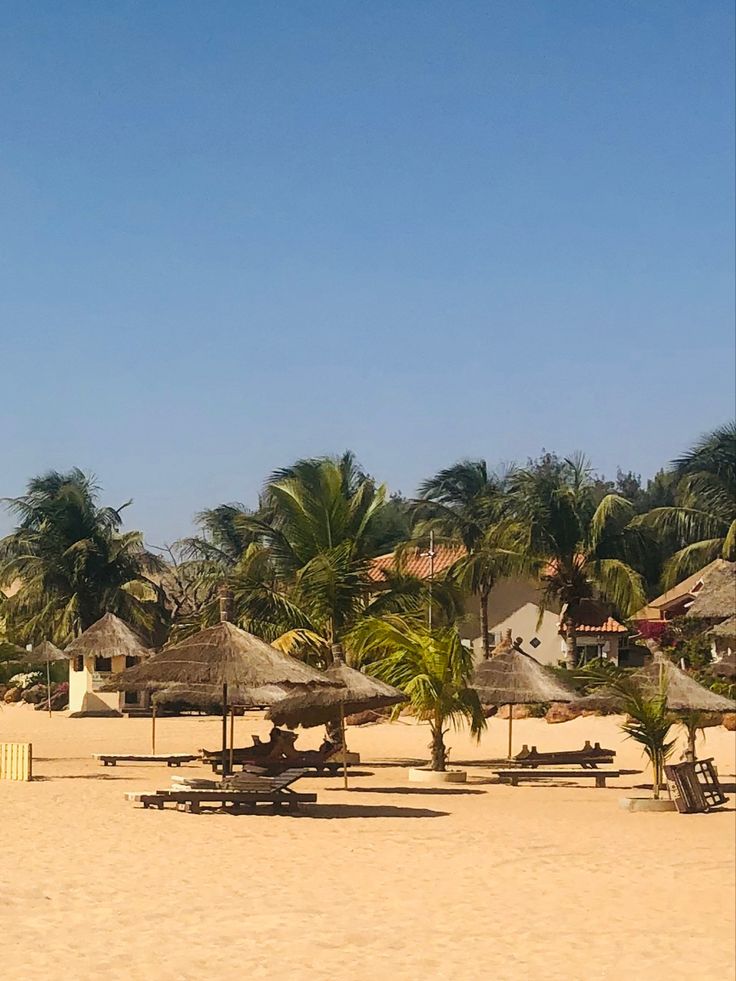 a sandy beach with palm trees and umbrellas