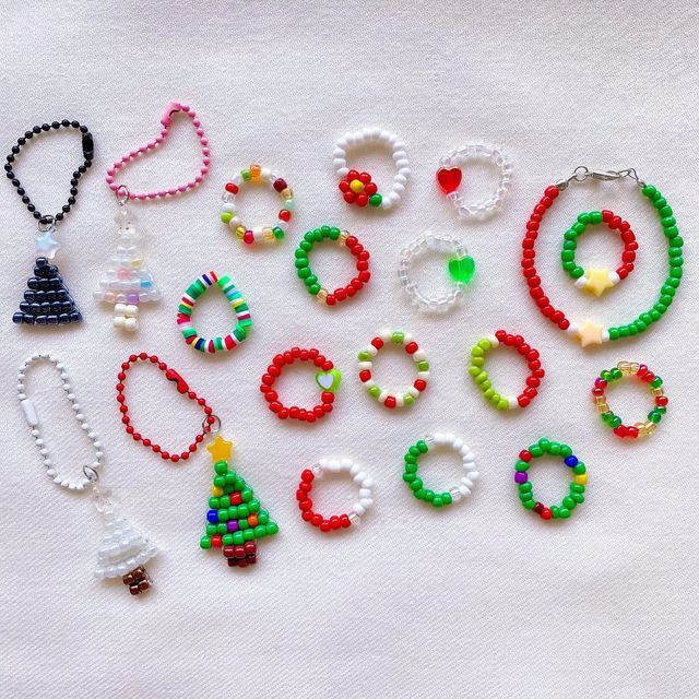 a bunch of beaded bracelets and necklaces on a white tablecloth with a small christmas tree in the middle