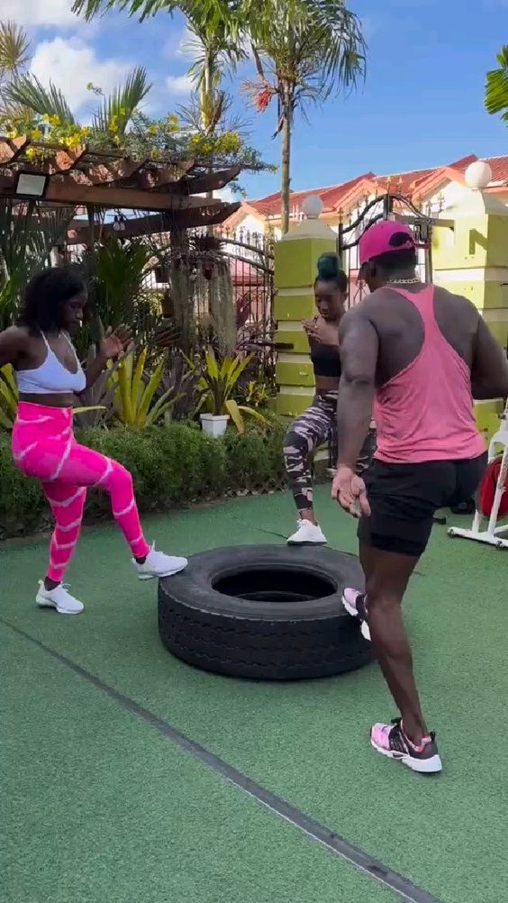 two women in pink shirts and black shorts playing with a tire