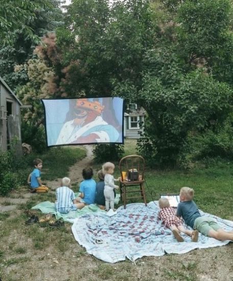 children sitting on blankets watching a movie in the backyard