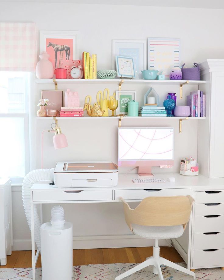 a white desk topped with a computer monitor next to a window filled with lots of clutter