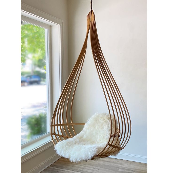 a hanging chair in front of a window with a white rug on the bottom floor