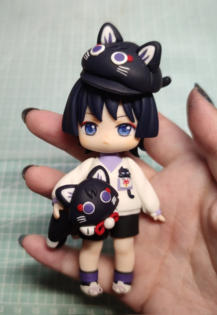 a hand holding a small black and white cat figurine